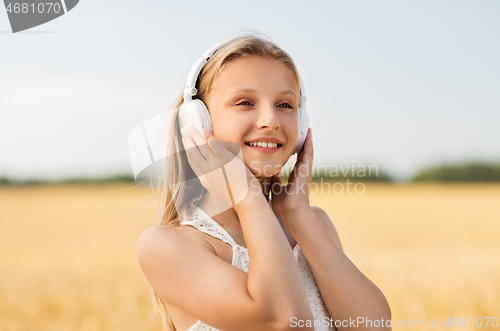 Image of happy girl in headphones on cereal field in summer