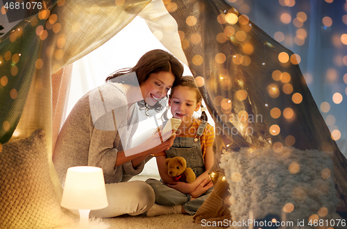 Image of happy family with smartphone in kids tent at home