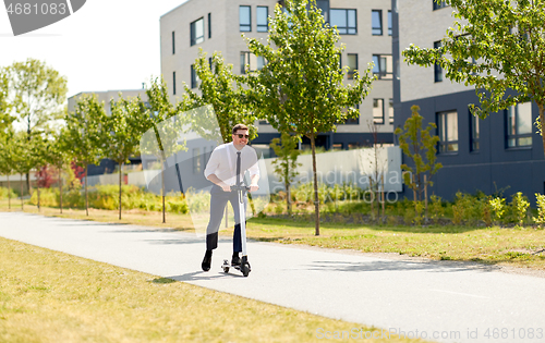 Image of young businessman riding electric scooter outdoors