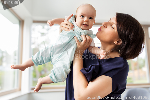 Image of middle-aged mother holding baby daughter at home