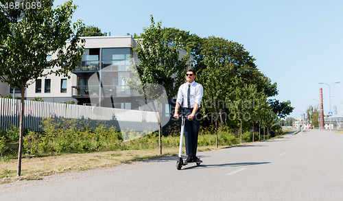 Image of young businessman riding electric scooter outdoors