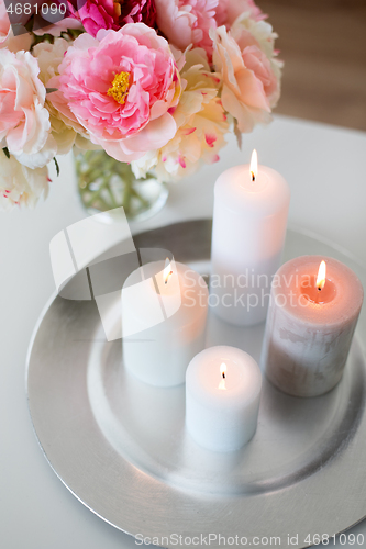 Image of candles burning on table and flowers at cozy home