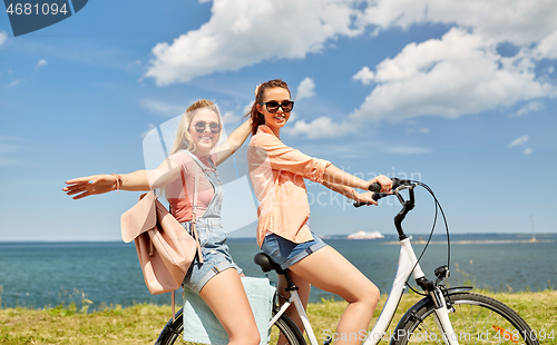 Image of teenage girls or friends riding bicycle in summer