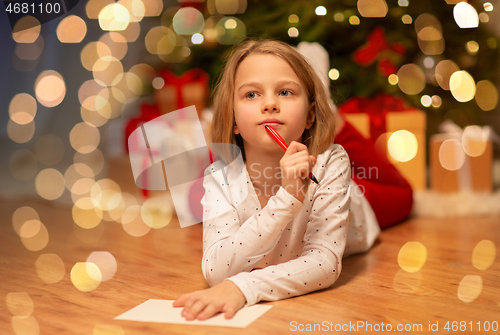 Image of girl writing christmas wish list at home