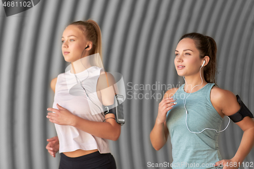 Image of young women with earphones and smartphones running