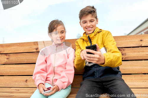 Image of children with smartphones sitting on street bench