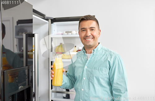 Image of man taking juice from fridge at home kitchen