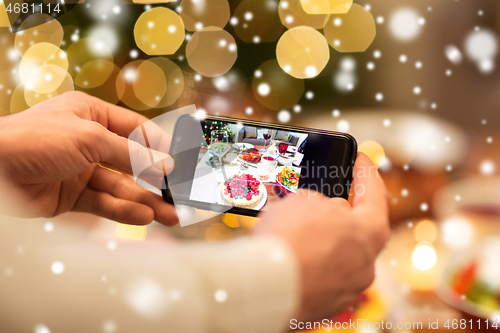 Image of hands photographing food at christmas dinner