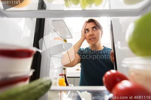 Image of crazy woman at open fridge holding to head