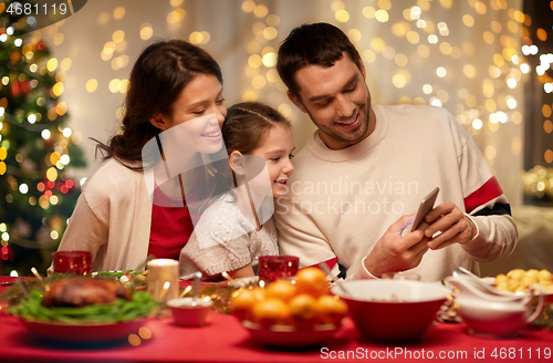 Image of family with smartphone having christmas dinner