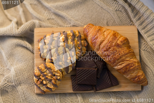 Image of croissant, chocolate and cookies on wooden board