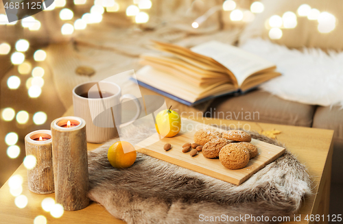 Image of cookies, lemon tea and candles on table at home