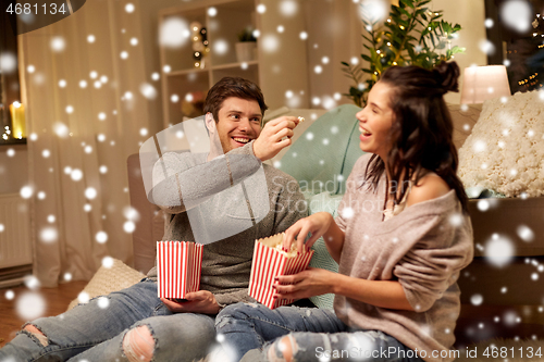 Image of happy couple eating popcorn at home