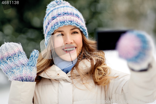 Image of woman taking selfie by smartphone in winter