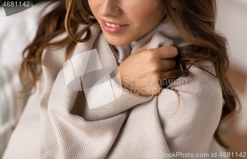 Image of close up of young woman wrapped in blanket at home