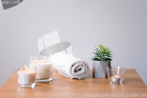 Image of burning fragrance candles and bath towel on table