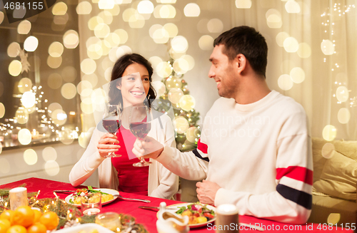 Image of happy couple drinking red wine at christmas dinner