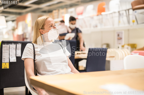 Image of New normal during covid epidemic. Caucasian woman shopping at retail furniture and home accessories store wearing protective medical face mask to prevent spreading of corona virus