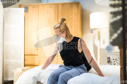 Image of New normal during covid epidemic. Caucasian woman shopping at retail furniture and home accessories store wearing protective medical face mask to prevent spreading of corona virus