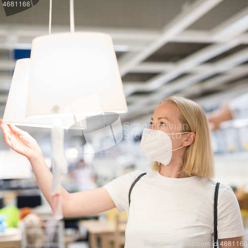 Image of New normal during covid epidemic. Caucasian woman shopping at retail furniture and home accessories store wearing protective medical face mask to prevent spreading of corona virus