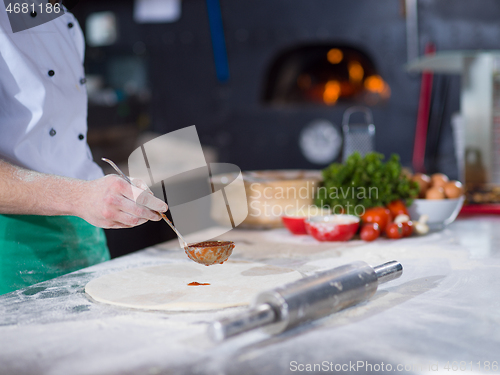 Image of Chef smearing pizza dough with ketchup