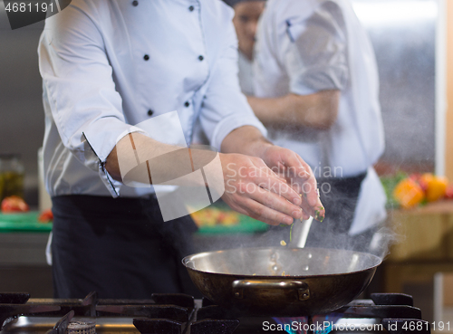 Image of chef preparing food, frying in wok pan