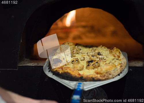 Image of chef removing hot pizza from stove