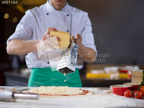 Image of chef sprinkling cheese over fresh pizza dough