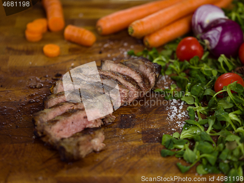 Image of Juicy slices of grilled steak on wooden board