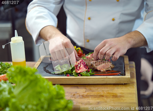 Image of closeup of Chef hands serving beef steak