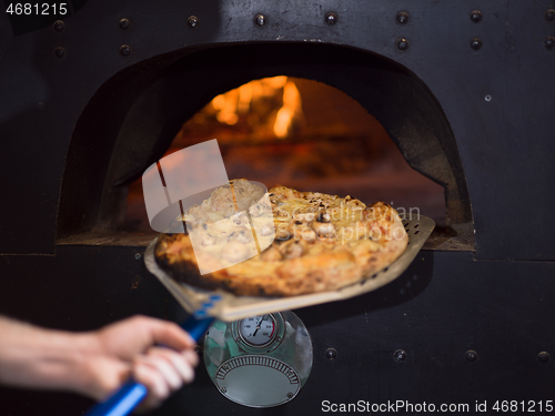 Image of chef removing hot pizza from stove