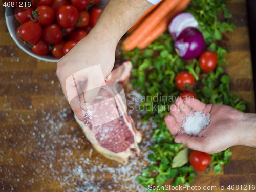 Image of Chef putting salt on juicy slice of raw steak