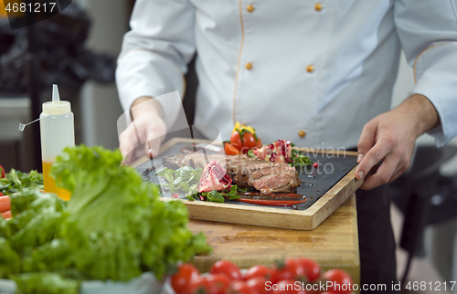 Image of closeup of Chef hands serving beef steak