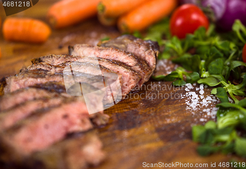 Image of Juicy slices of grilled steak on wooden board