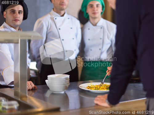 Image of chefs in the kitchen presenting dish of tasty meal