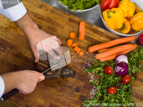 Image of closeup of Chef hands preparing beef steak