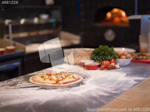 Image of chef putting fresh vegetables on pizza dough