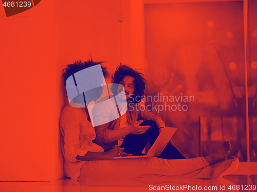 Image of multiethnic couple using a laptop on the floor