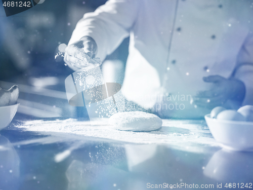 Image of chef sprinkling flour over fresh pizza dough