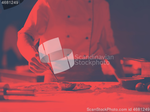 Image of Chef smearing pizza dough with ketchup