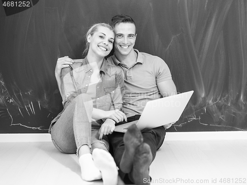 Image of couple using laptop in front of gray chalkboard