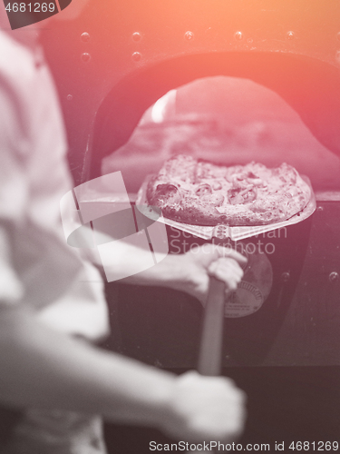 Image of chef removing hot pizza from stove