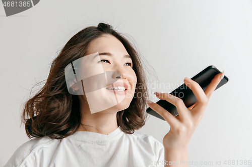 Image of Indoor portrait of attractive young asian woman holding blank smartphone