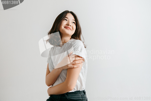 Image of Happy asian woman standing and smiling against gray background.