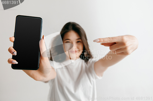 Image of Portrait of a confident casual asian girl showing blank screen of mobile phone