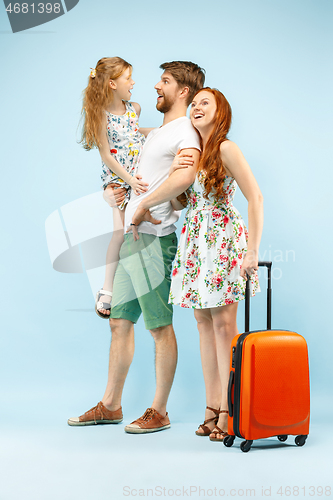 Image of Happy parent with daughter and suitcase at studio isolated on blue background