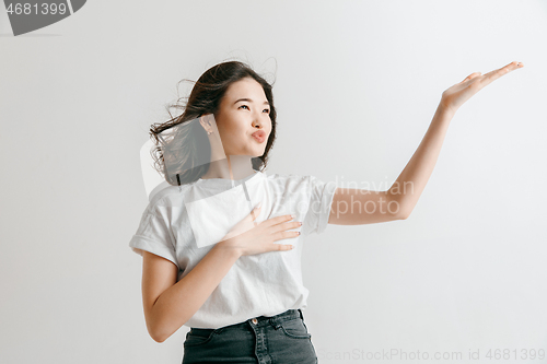 Image of The happy asian woman standing and smiling against gray background.