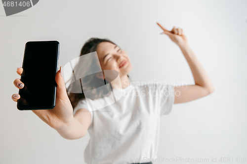 Image of Portrait of a confident casual asian girl showing blank screen of mobile phone