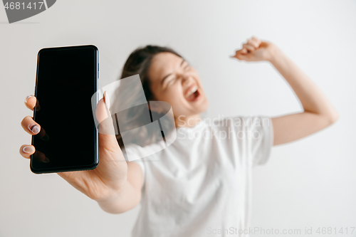 Image of Portrait of a confident casual asian girl showing blank screen of mobile phone