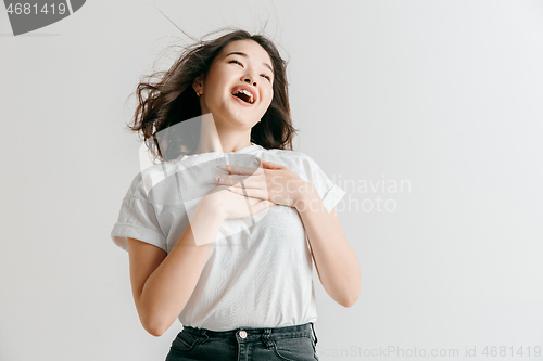 Image of Happy asian woman standing and smiling against gray background.